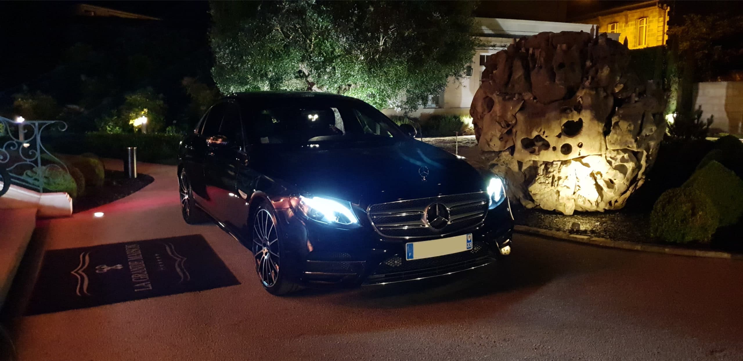 La voiture d'Aquitaine Business Driver, garée devant un hôtel, en pleine nuit, pour vous assurer des transferts de qualité, de jour comme de nuit.